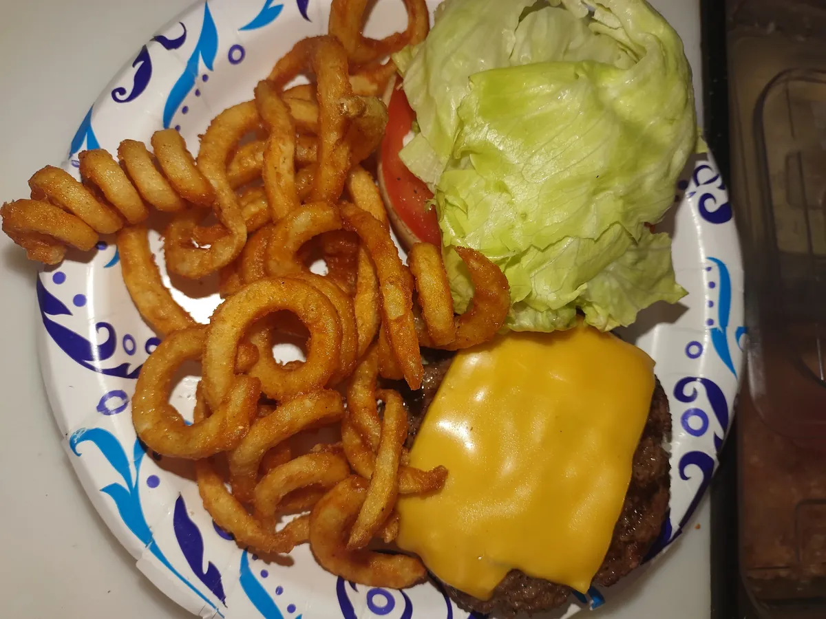 Cheeseburger plate with curly fries, lettuce, and tomato