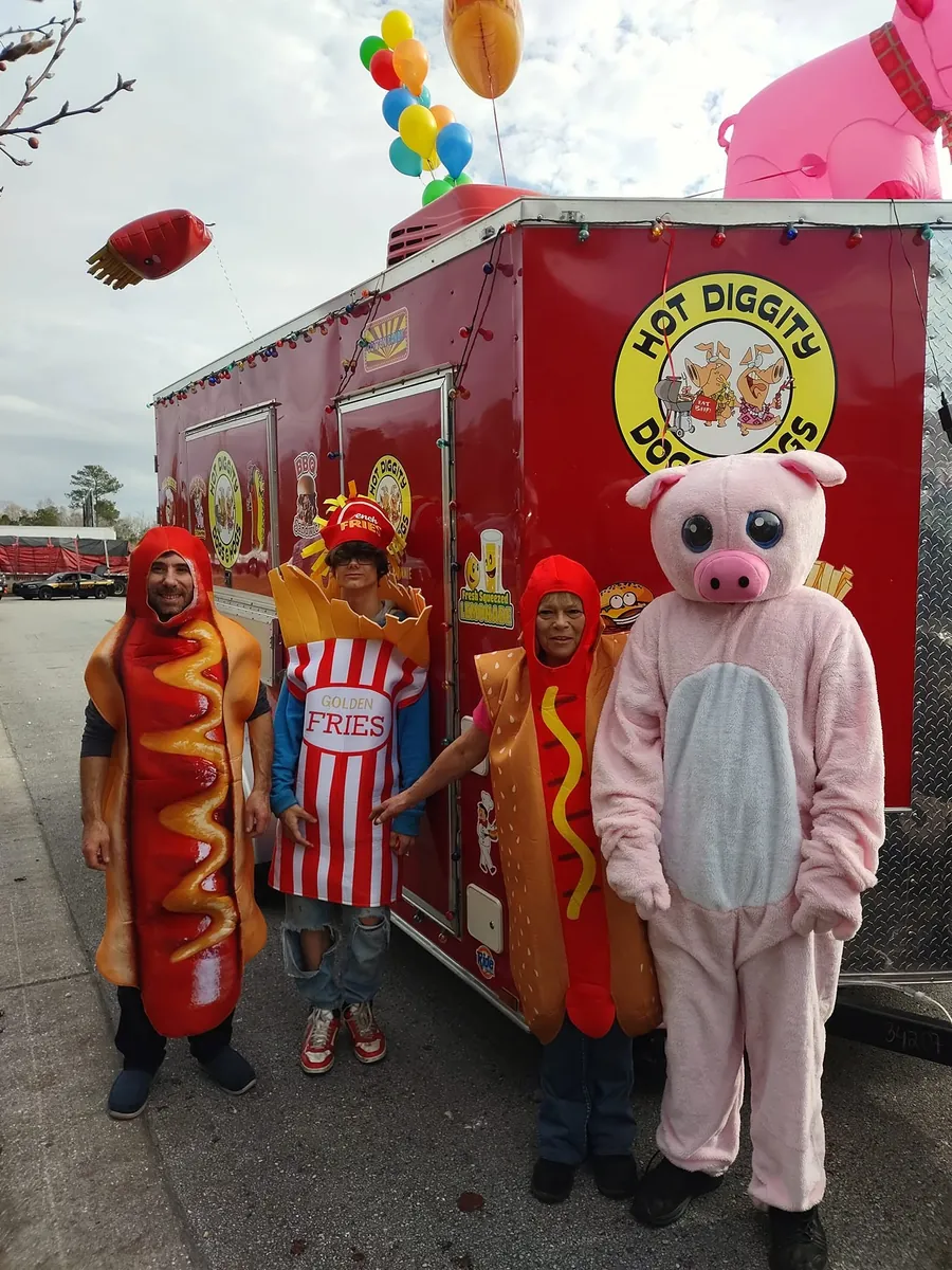 The crew in hot dog, fries, and pig costumes in front of the trailer