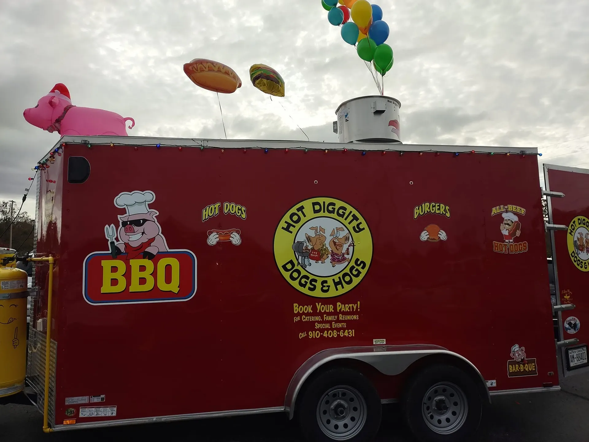 The bright red Hot Diggity Dogs and Hogs trailer with a pink pig balloon on the roof