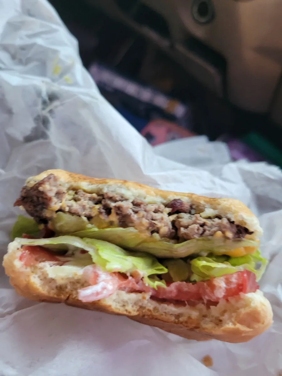 Cross-section of a hand-pattied burger stacked with lettuce, tomato, and toppings