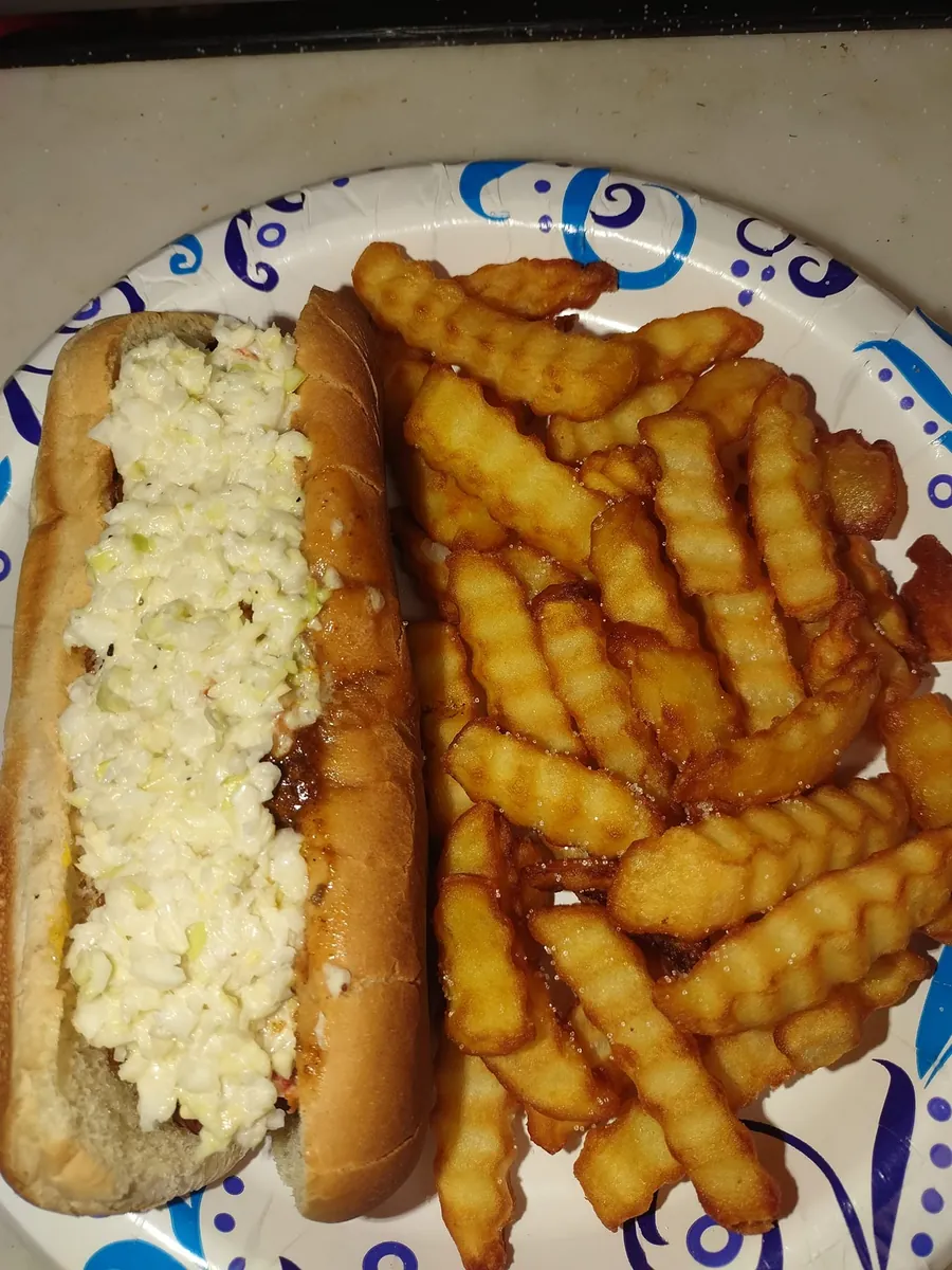 Slaw dog with crinkle-cut fries on a plate